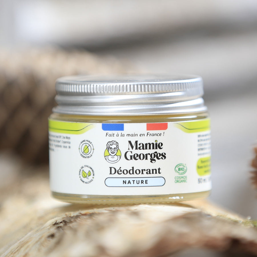 Pot de déodorant Nature de Mamie Georges sur une bûche de bouleau, une pomme de pin à côté