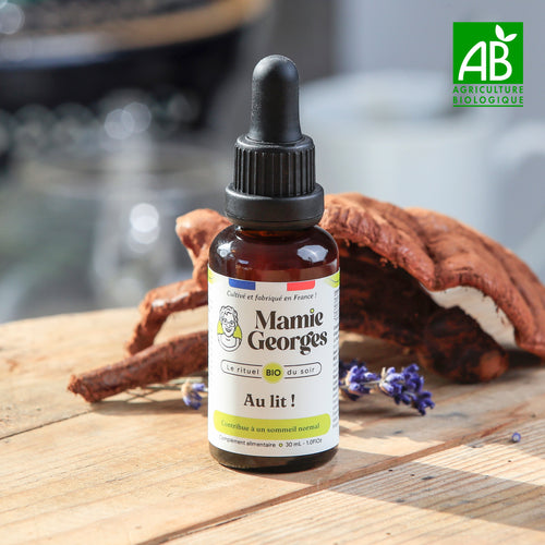 Flacon Au lit ! de Mamie Georges, fermé, sur une table en bois devant un reishi, avec le logo AB Agriculture biologique